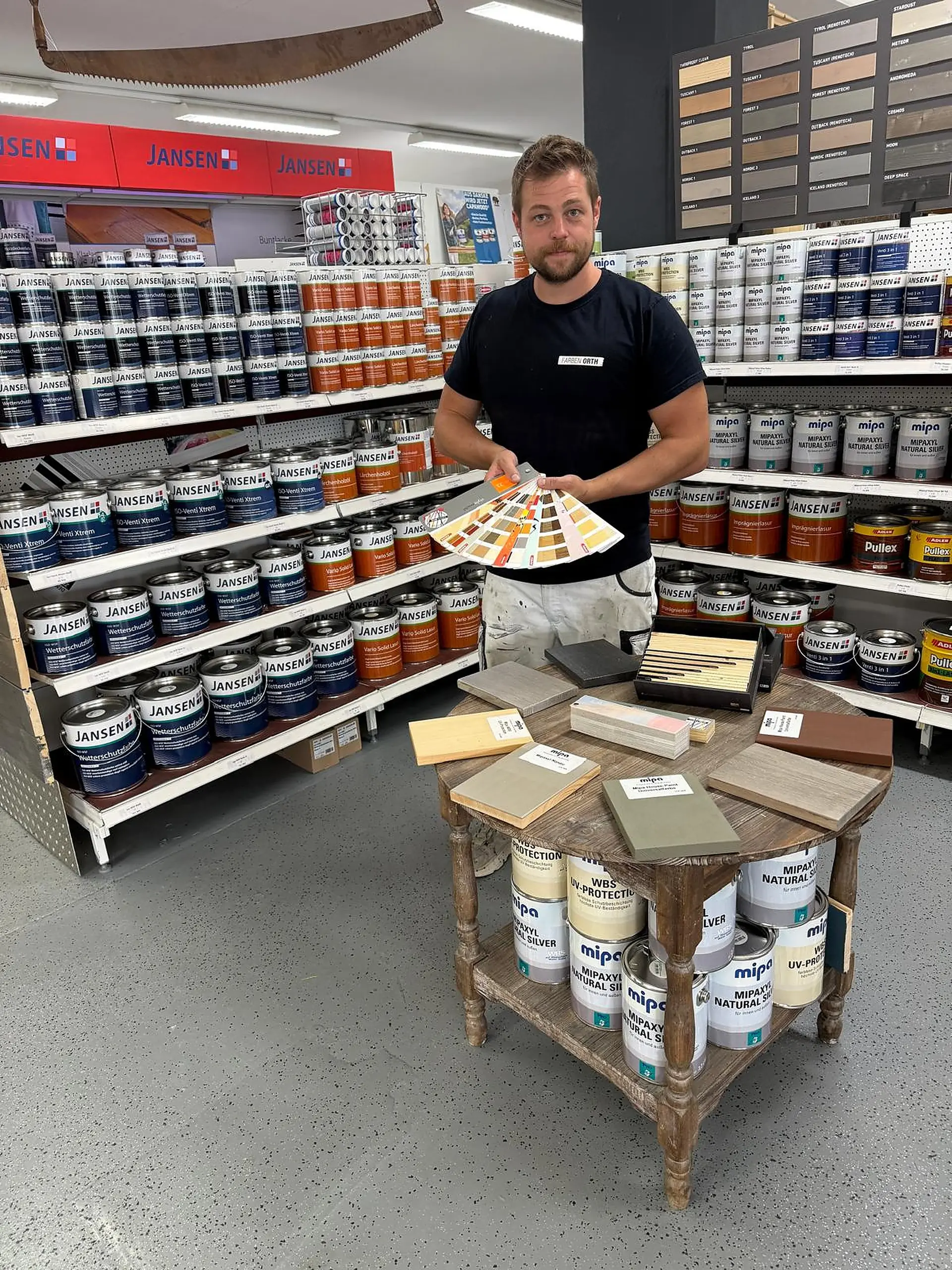 Jakob Orth im Fachmarkt mit Farbfächer und Holzmustern
